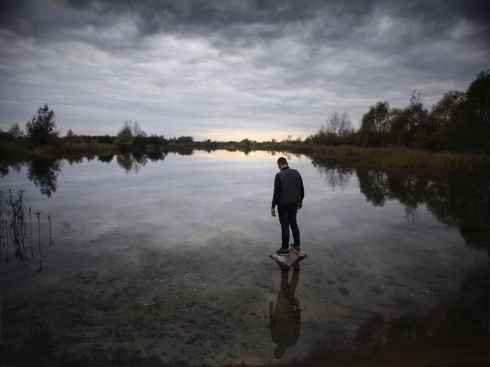 Man standing in lake against sky