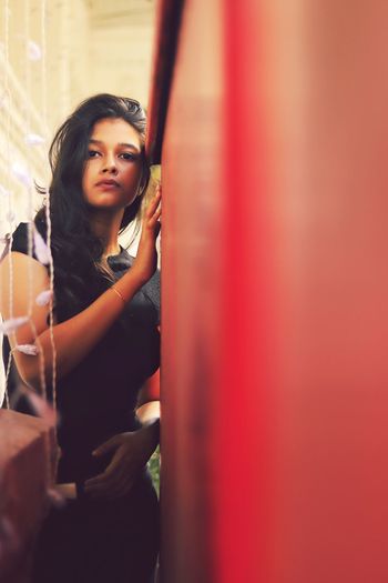 Portrait of woman standing by red wall at home
