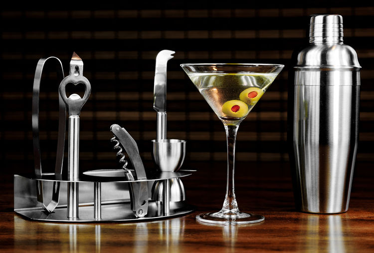 Bartending tools and martini glass on wooden table at bar