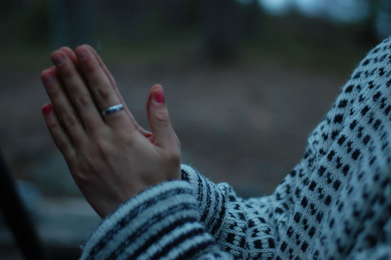 Midsection of woman with hands clasped standing outdoors