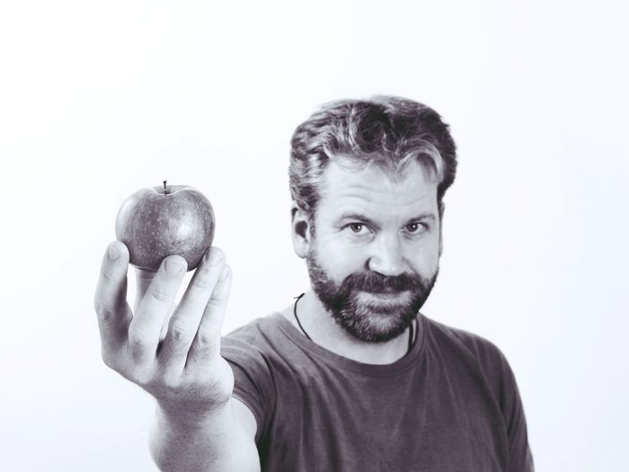 Portrait of man with apple against white background