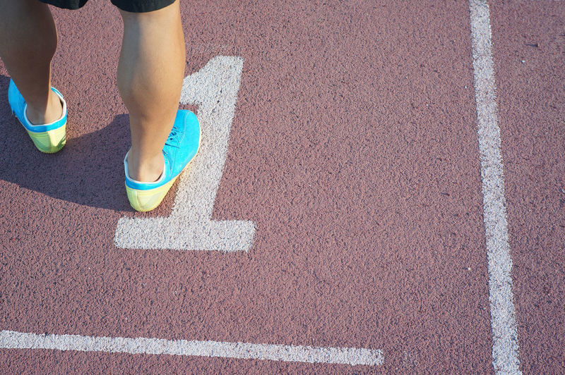 Low section of person standing over number on running track