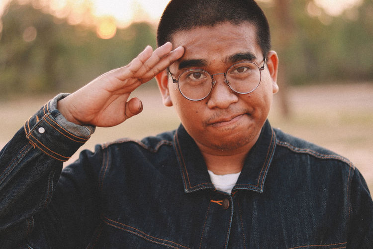 Portrait of young man saluting against defocused background