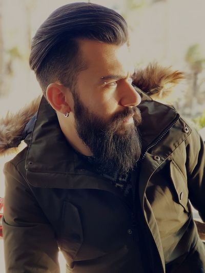 Close-up of thoughtful man with beard wearing warm clothing
