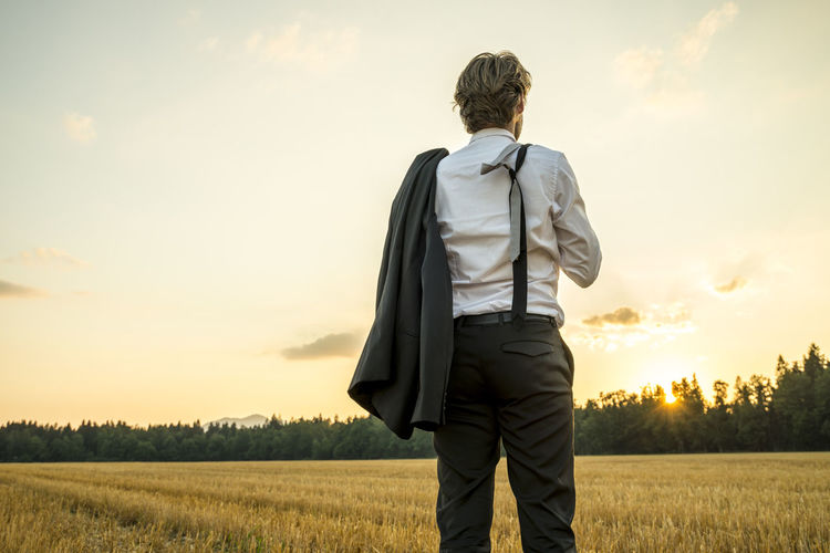 Rear view of man standing on field against sky