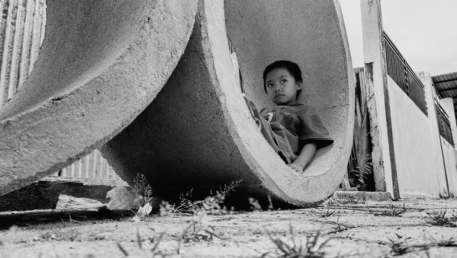 Boy looking away while sitting in pipe
