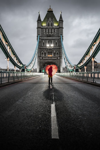 Young woman in yellow raincoat standing on empty tower bridge in london, england