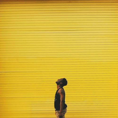 Man standing against yellow shutter