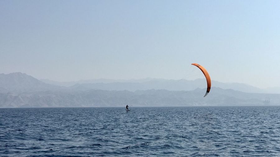 Person kiteboarding in sea against clear sky