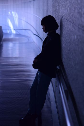Side view of young woman looking away while sitting on wall