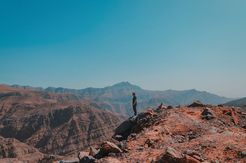 Full length of man standing on rocky mountain against sky