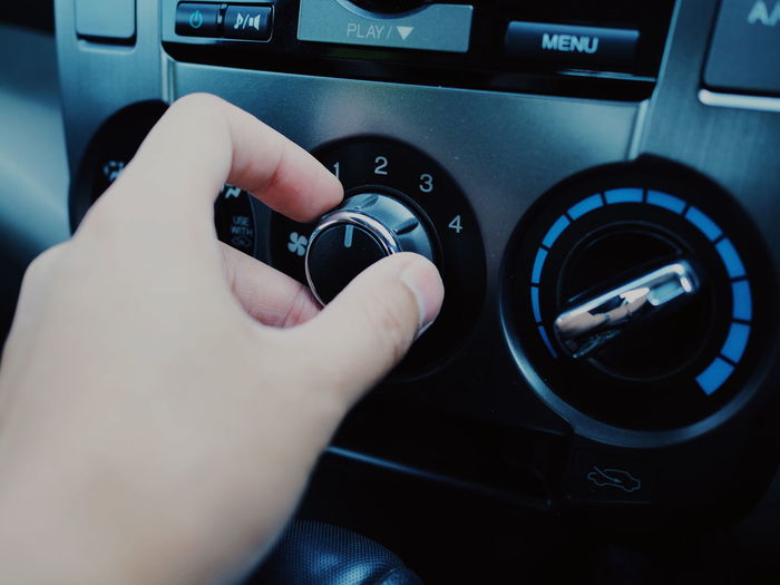 Cropped hand adjusting knob of music stereo in car 