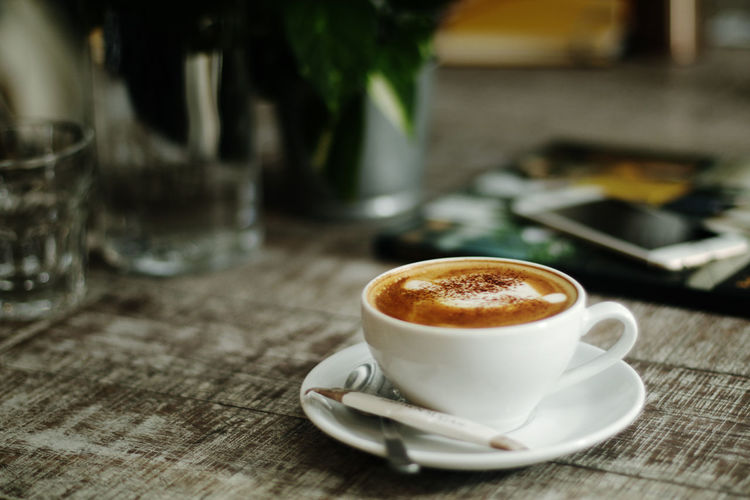 Cup of latte on a wooden table in a cafe.