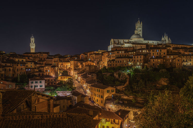 Amazing night cityscape with two iconic landmarks, torre del mangia and the cathedral of siena