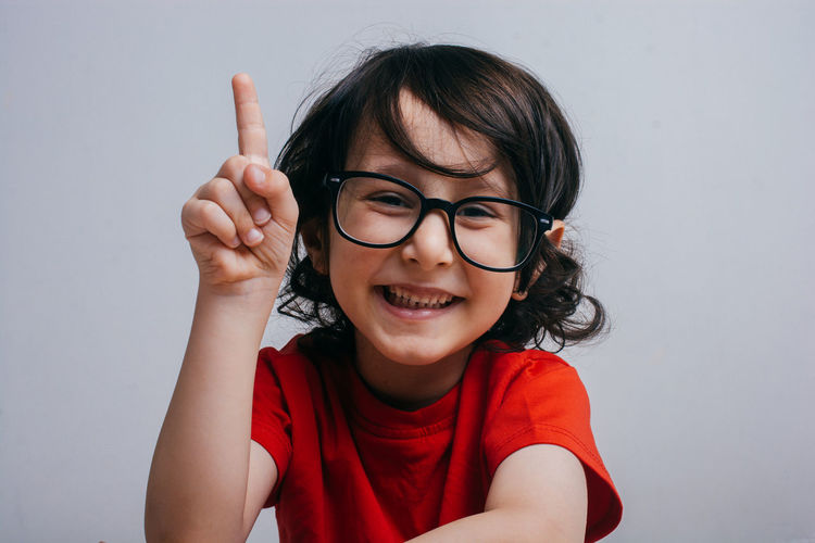 Portrait of smiling boy in eyeglasses on white background
