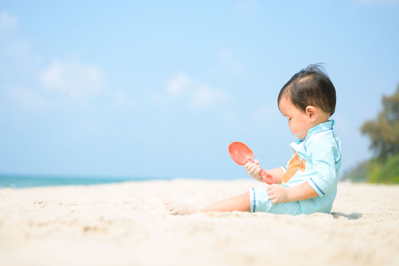 Boy wearing sunglasses on beach against sky