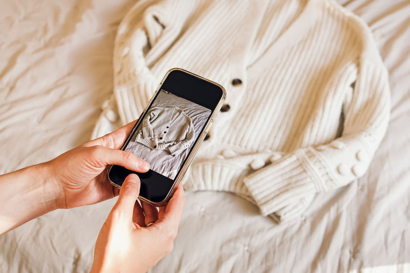 Close-up of woman's hands taking picture of her clothes. selling used clothes online, reuse 