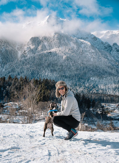 Man and french bulldog against winter mountain