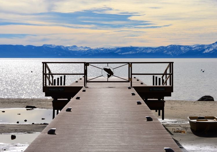 Man relaxing on table by sea against sky