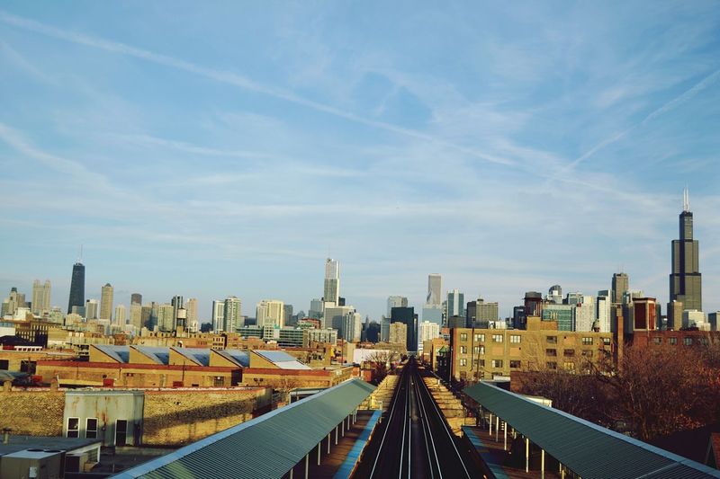 Railroad tracks amidst modern buildings against sky in city