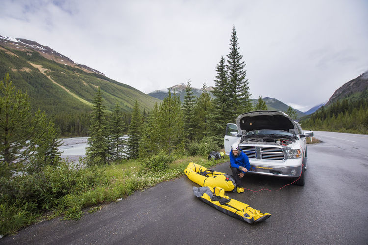 Man using power from truck battery to inflate river kayaks, packrafts.