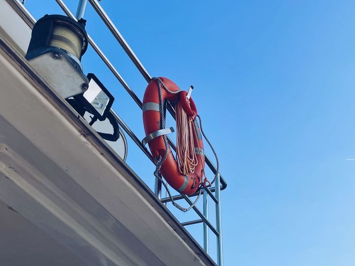 Low angle view of red ship against clear blue sky