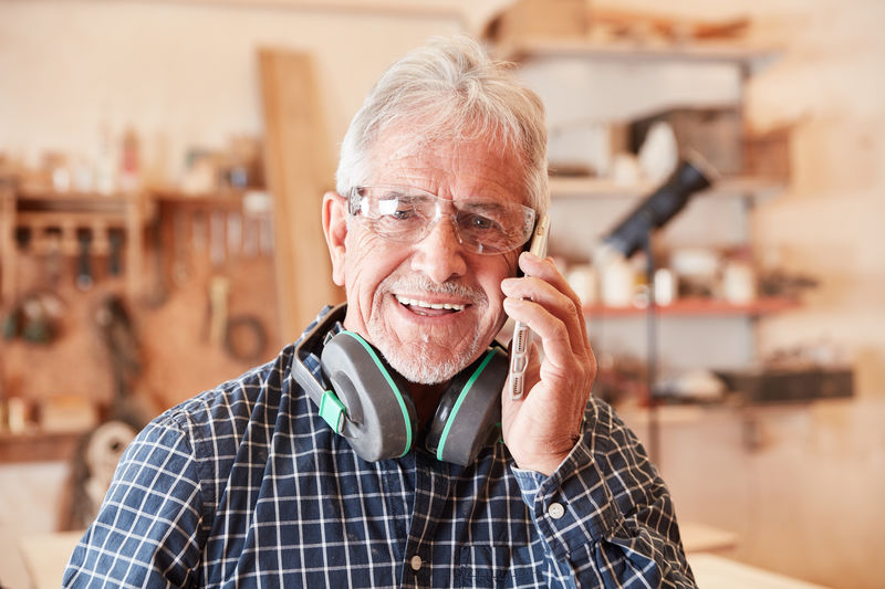Portrait of smiling carpenter talking on phone at workshop