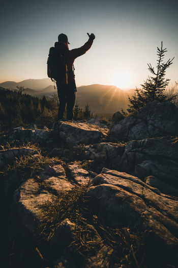 Man gesturing while standing on mountain against sky
