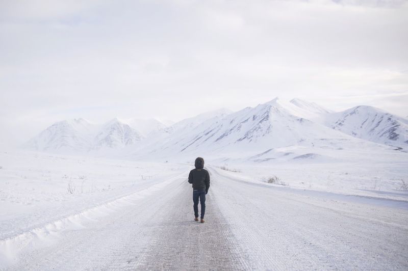 Rear view of man standing on snow covered mountain