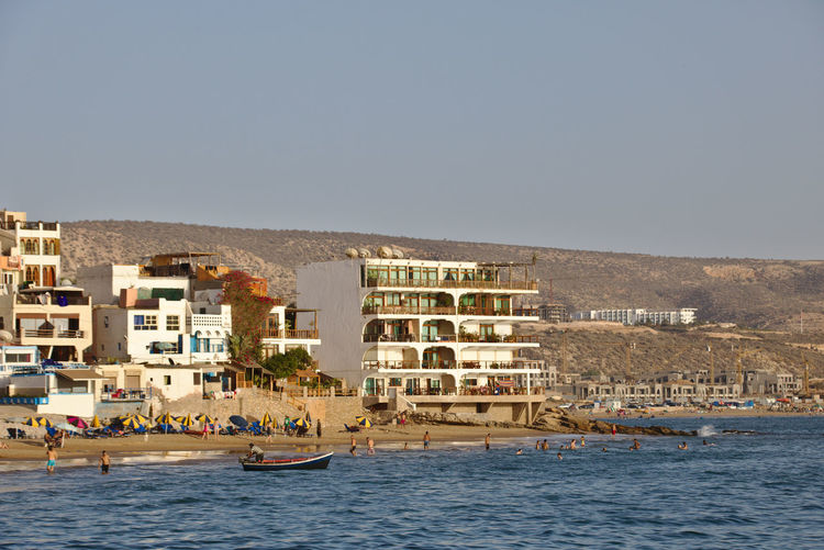 Scenic view of sea by buildings against clear sky