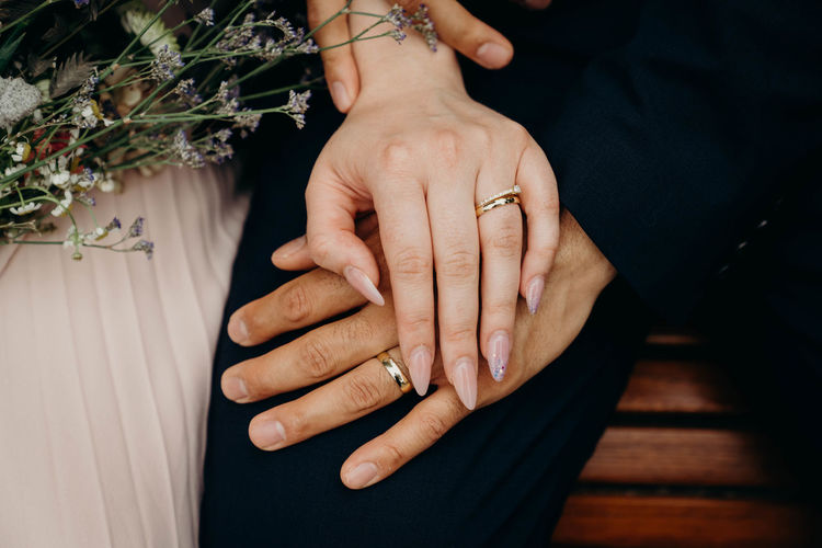 MIDSECTION OF COUPLE HOLDING HANDS ON TABLE