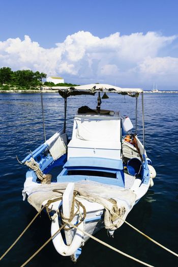 Boats moored in calm blue sea against sky