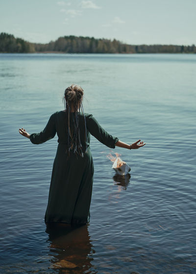 Rear view of woman standing in lake