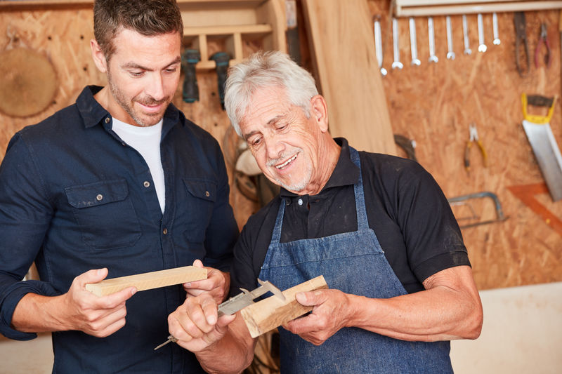 Men discussing over wood in workshop