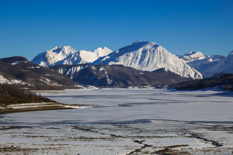 Frozen artificial dam of camposto with high mountains in the background, abruzzo