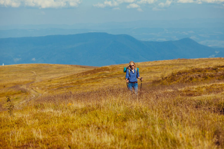 Woman walking on field against landscape