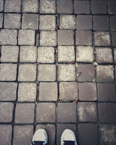 High angle view of shoes on cobblestone footpath