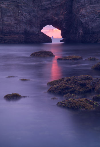Scenic view of sea and rock formation against sky during sunset