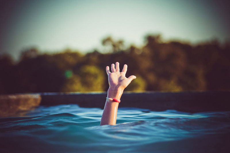 Cropped hand emerging from swimming pool