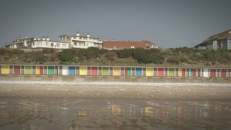 Colorful beach huts at shore against sky