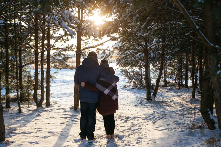 Rear view of couple walking on snow covered land