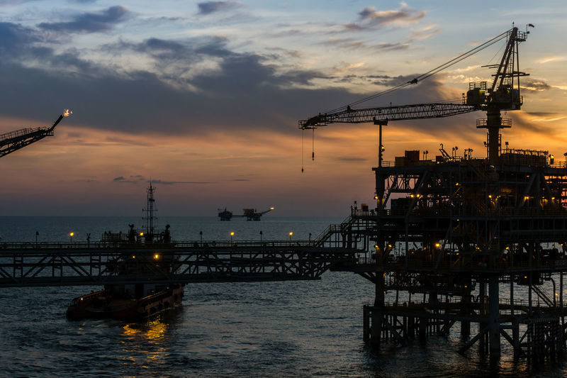 Sunset at oil field with silhouette of oil production platform 