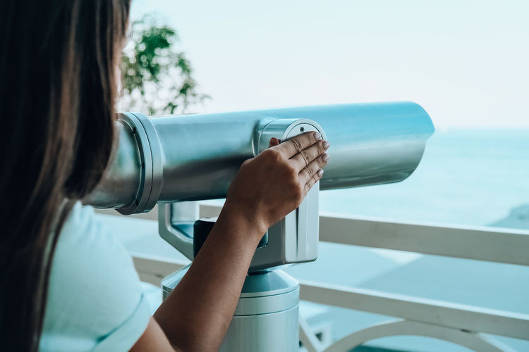 Woman looks through binoculars at the sea. traveler vacation holiday concept. new travel destination