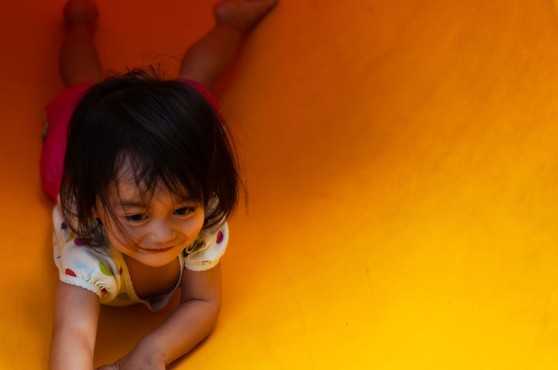 High angle view of cute girl lying on yellow slide