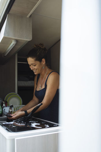 Woman with bun washing dishes in motorhome during a vacation.