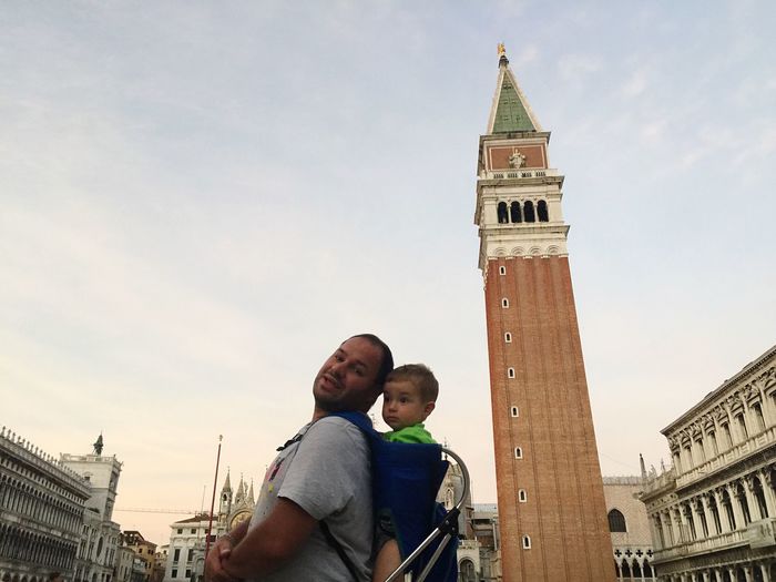 Portrait of father with son standing by st mark campanile on street against sky