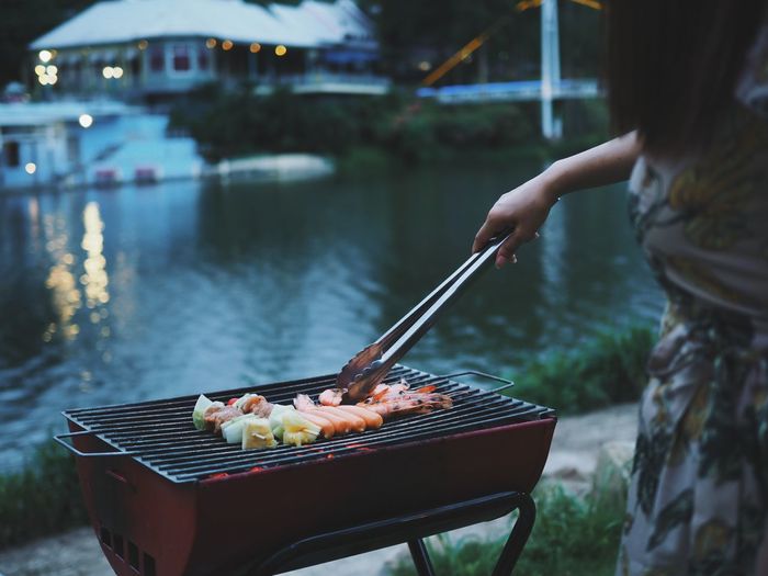 Midsection of woman preparing food on barbecue grill