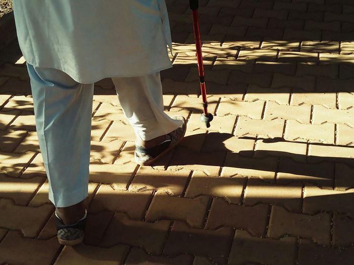 Low section of man with walking cane on footpath