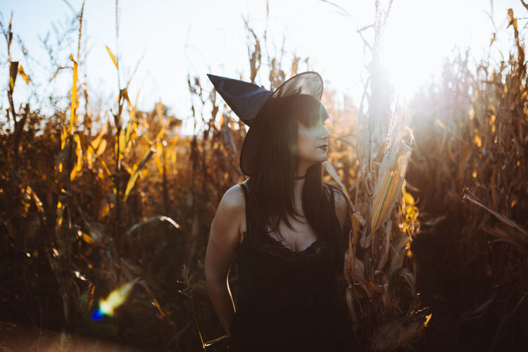 Woman wearing witch hat while standing at farm