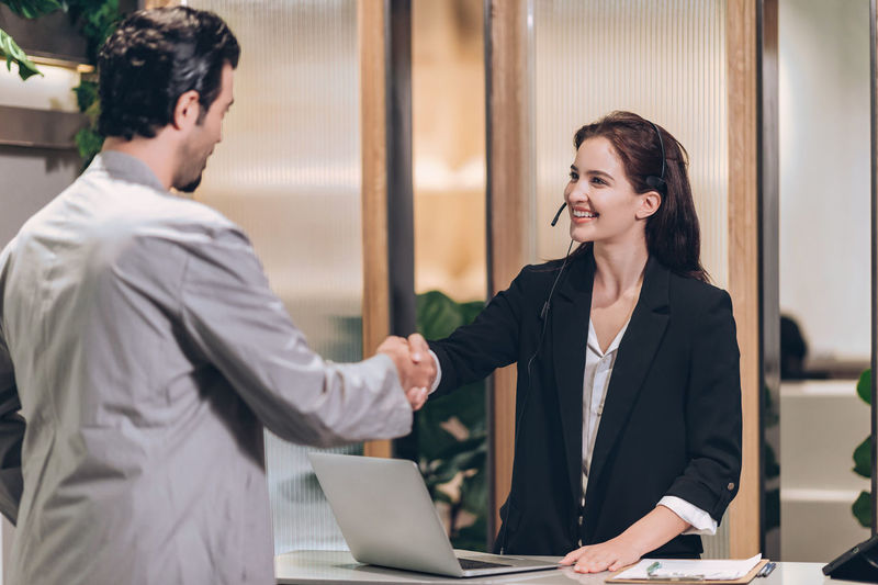 Receptionist welcome businessman at hotel front desk